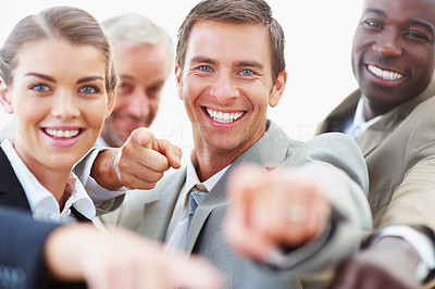 Cheerful business people pointing towards camera and smiling
