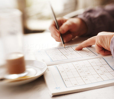 Woman trying to solve Sudoku Puzzle - window, sunlight, and coffee