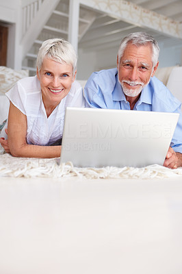 An aged old couple relaxing with laptop in front