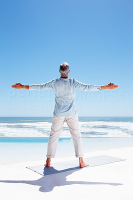 Rear view of an old man with hands stretched, exercising on the beach
