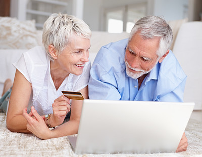 Happy elderly couple purchasing from the net using a credit card
