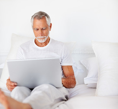 An elder senior male working on a laptop