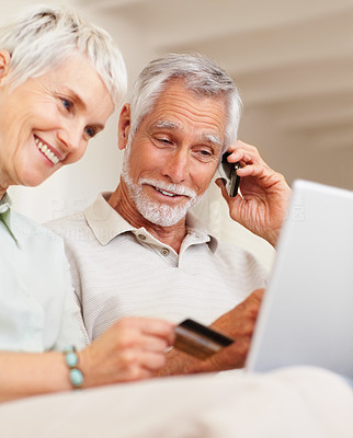 Cute elderly couple using the convenience of shopping from the net with a credit card