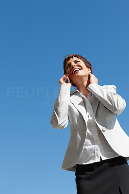 Pretty business woman speaking on her cellphone with the sky at the back