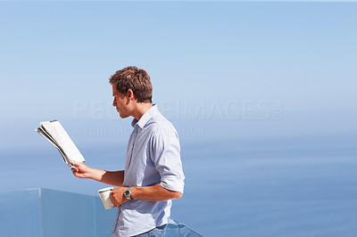 Young business man reading a newspaper with blue sky at the background