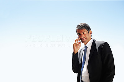 Mature business man speaking on the phone with the blue sky as the background