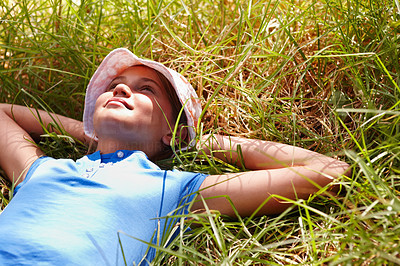 Sweet young girl with her hands behind her head and resting on grass