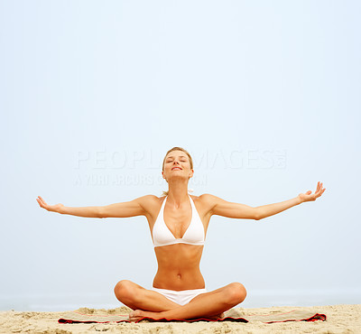 Happy young woman practicing yoga by stretching her hands at the beach