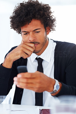 Confused young business man using his cellphone