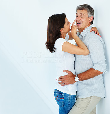 Happy mature couple in a playful mood fondling eachother over a white background