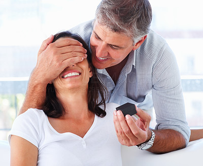 Happy mature man covering his wife\'s eyes to surprise her with a ring