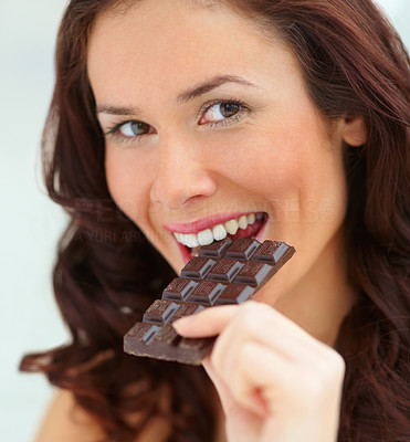 Closeup portrait smiling young female eating a chocolate bar