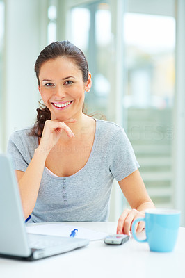 Smiling young female sitting with coffee cup and laptop