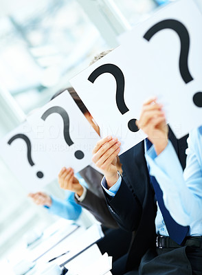 Colleagues holding question mark on boards in the conference room