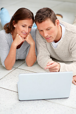Beautiful couple on the floor with a laptop in front