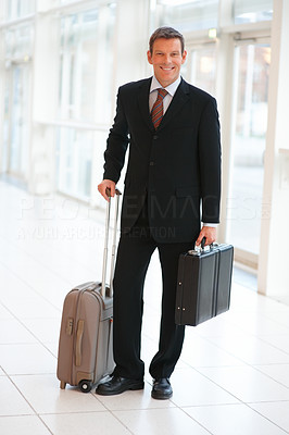 Confident young business man holding a suitcase and bag