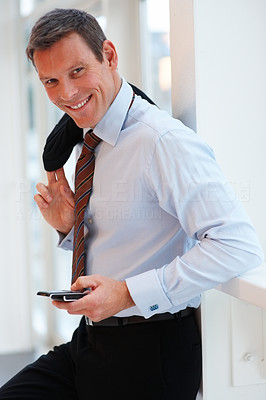 Young business man leaning on the wall while using a cellphone