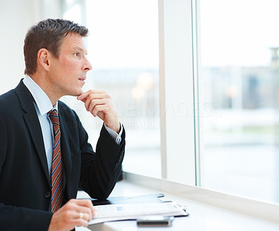 Portrait of a smart young business man looking out of the window and thinking