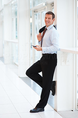 Handsome business man leaning on the wall while holding a cellphone