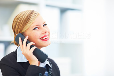 Closeup portrait of a smiling businesswoman holding a telephone receiver