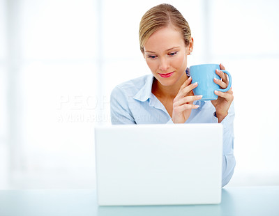 Young business woman drinking coffee and using a laptop