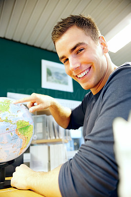 Young man pointing at globe in classroom