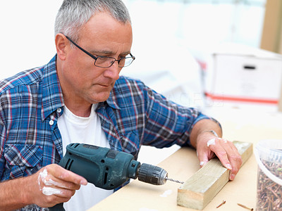 Mature carpenter drilling a hole in wood