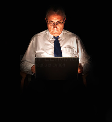 Senior business man working on laptop in the dark