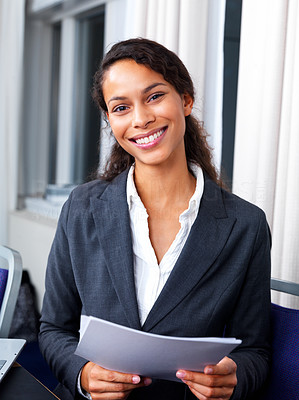 Happy business woman standing in office holding paper in hand