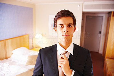 Traveling businessman straightening his tie in a hotel room