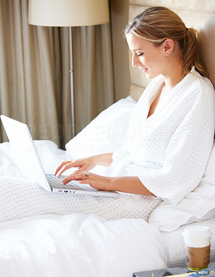 Happy lady sitting on bed and using laptop