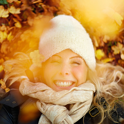Closeup of a beautiful woman lying on ground covered with leaves and smiling