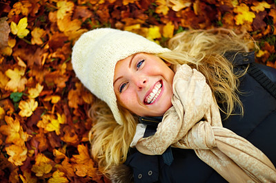 Closeup of a beautiful woman lying on ground covered with leaves and smiling