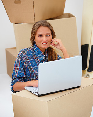 Woman sitting by box using laptop - copyspace
