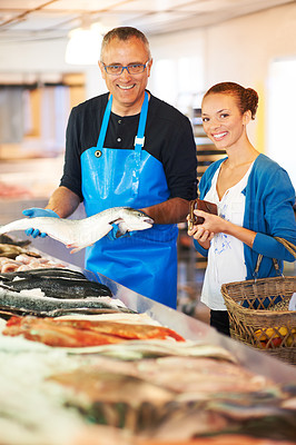 A fishmonger showing a big fish to a customer