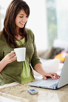 Cute brunette working on a laptop , having coffee at home