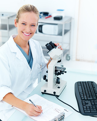 Happy young female researcher using microscope