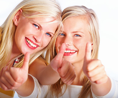 Closeup of two happy pretty women showing thumbs up sign against white background