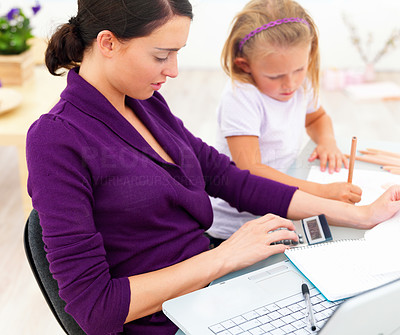 Mother and daughter sitting by desk with laptop, documents and calculator