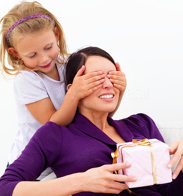 Daughter closing eyes of mother holding gift on white