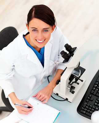 Female researcher with microscope and writing notes