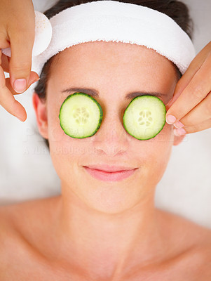Closeup of cucumber slices on a smiling young girl\'s eyes