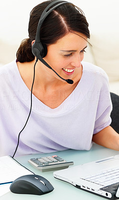 Closeup of a happy beautiful young business woman with headset at desk using a laptop