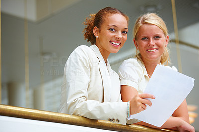 Two smiling business women conversing over a document
