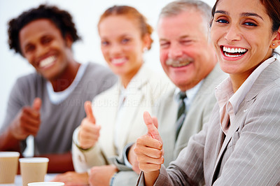 Closeup portrait of a smiling business woman with executives showing thumbs up against white