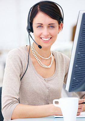 Portrait of a happy young woman at desk with headset