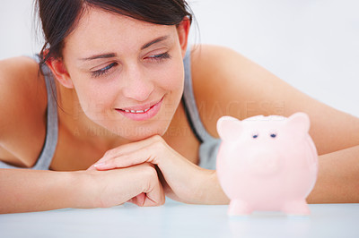 Portrait of a happy young lady looking at piggybank