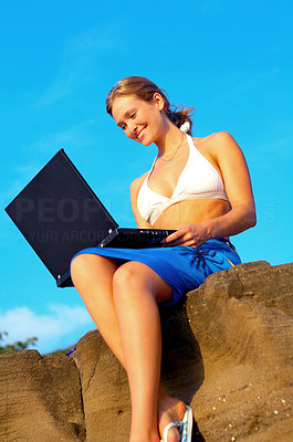 Beautiful Young Woman on the Rocks by the Sea with Laptop