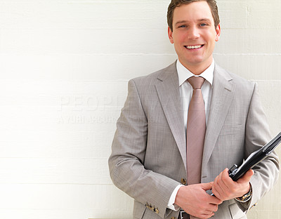 Successful handsome business man smiling, standing against white background holding a folder