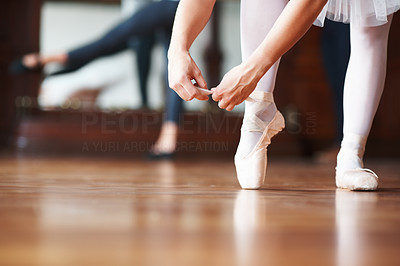 Ballerina putting on pointes with a blurred man in background